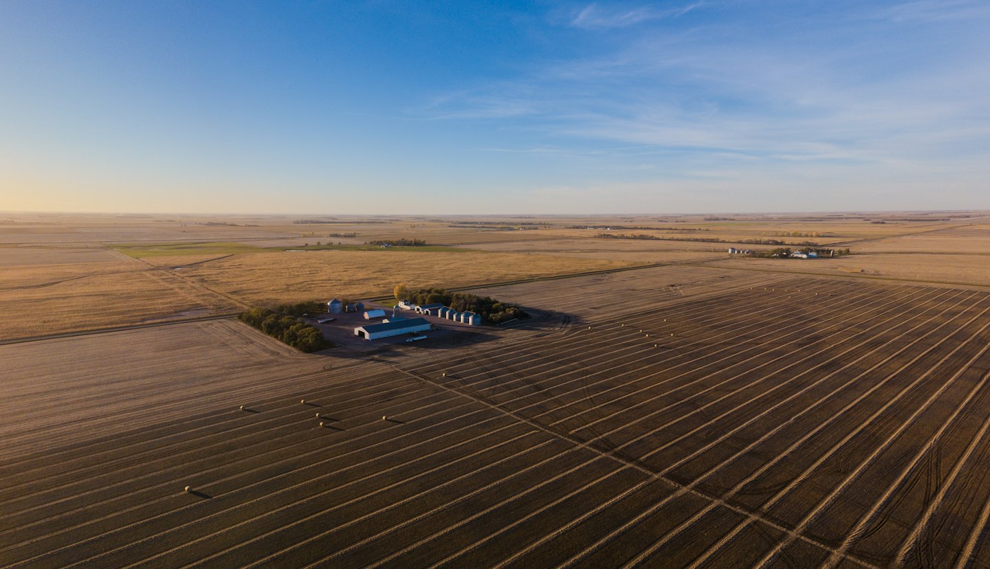 Farmstead with grain silos surrounded by vast agricultural fields.